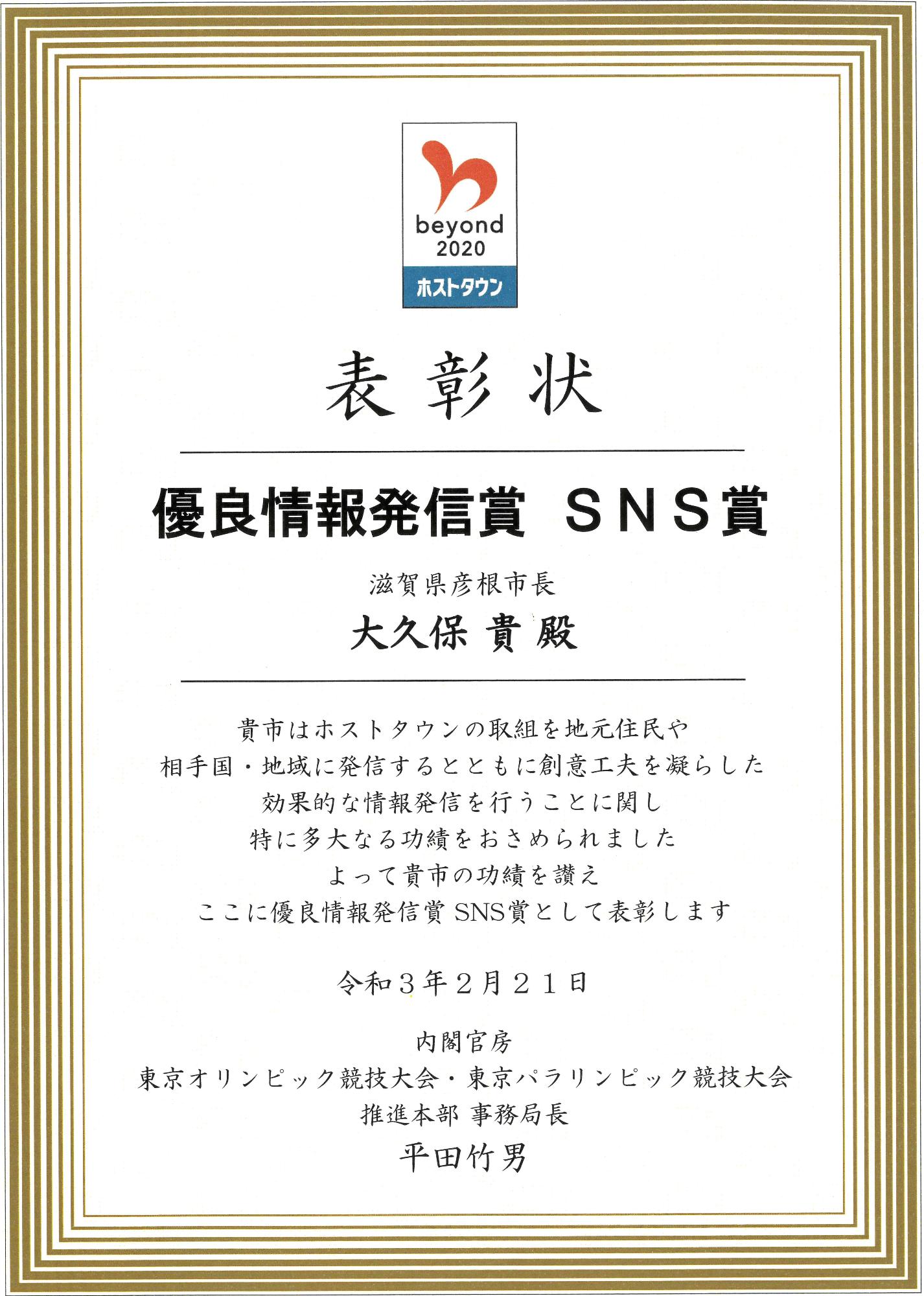 表彰状「優良情報発信賞SNS賞 滋賀県彦根市長大久保貴殿 貴市はホストタウンの取組を地元住人や相手国・地域に発信するとともに創意工夫を凝らした効果的な情報発信を行うことに関し特に多大な功績をおさめられました。よって貴市の功績をたたえ、ここに優良情報発信賞SNS賞として表彰します。令和3年2月21日内閣官房東京オリンピック競技大会・東京パラリンピック競技大会推進本部事務局長平田竹男