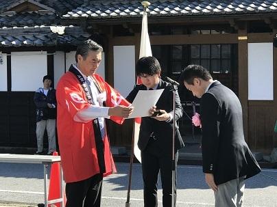 表彰式で表彰状を読み上げる市長の写真