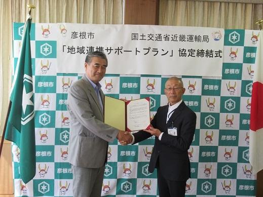 国土交通省近畿運輸局様と協定書を手に握手をしている市長の写真