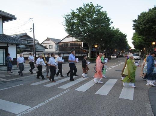 参加者とともに万灯を手に横断歩道を渡る市長の写真