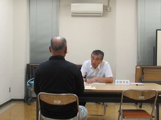 黒い服を着た高齢男性と対話している市長の写真