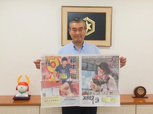 新聞記事を手に持っている市長の写真