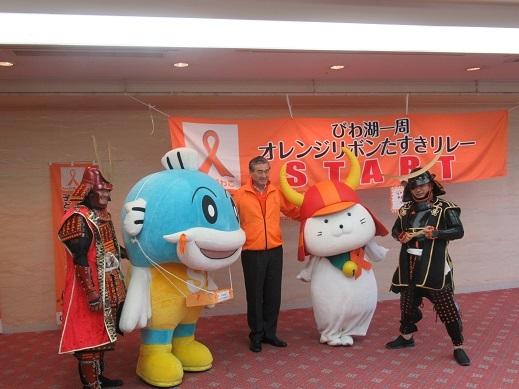 スタートセレモニーで兜を着用した人とキャラクターとの記念写真