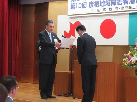 彦根市優良従業員表彰式で表彰状を読み上げている市長の写真