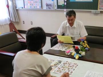 校長先生と向かい合って座り資料を見ながら話をしている市長の写真
