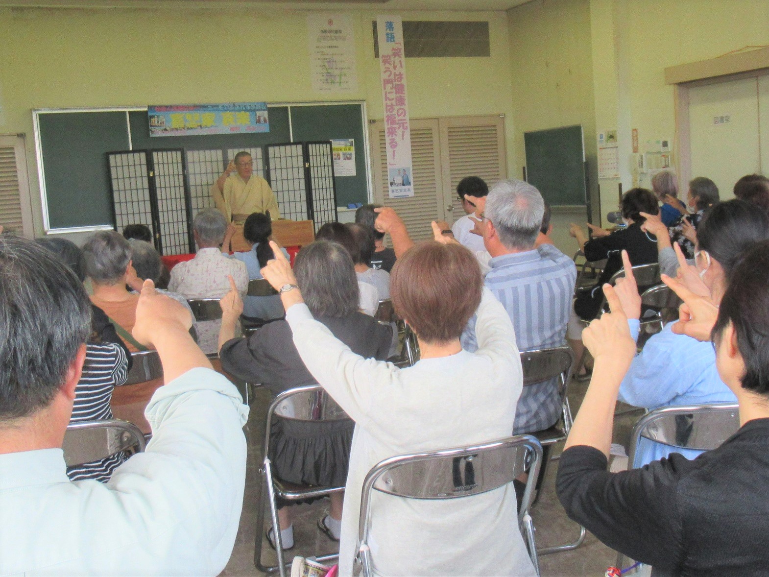 寄席中観客も一緒に手振りをする様子