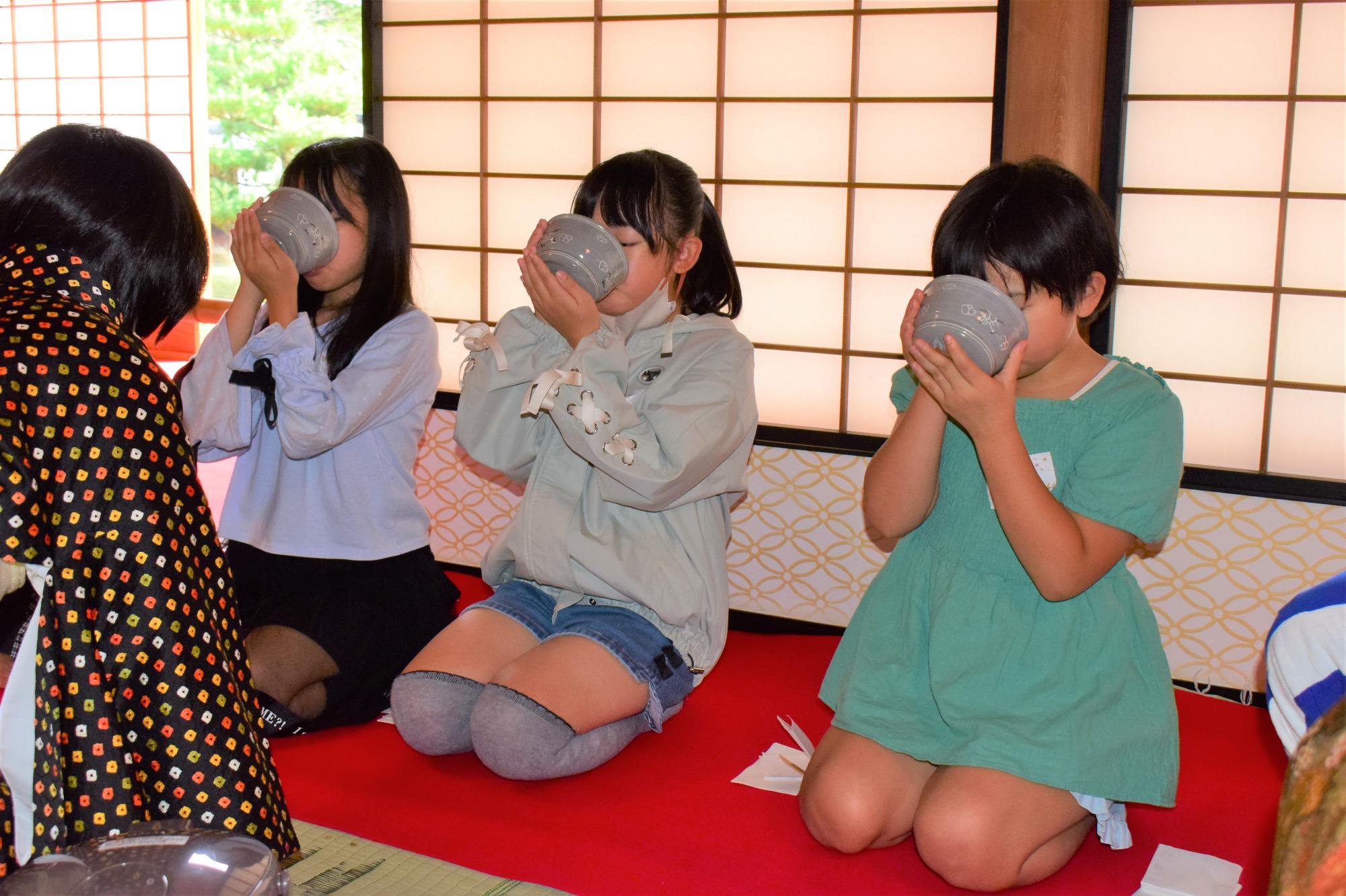 お茶を飲む3人の子どもの写真