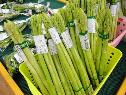 バスケットに入って売られているきれいな緑色をしたアスパラガスの写真