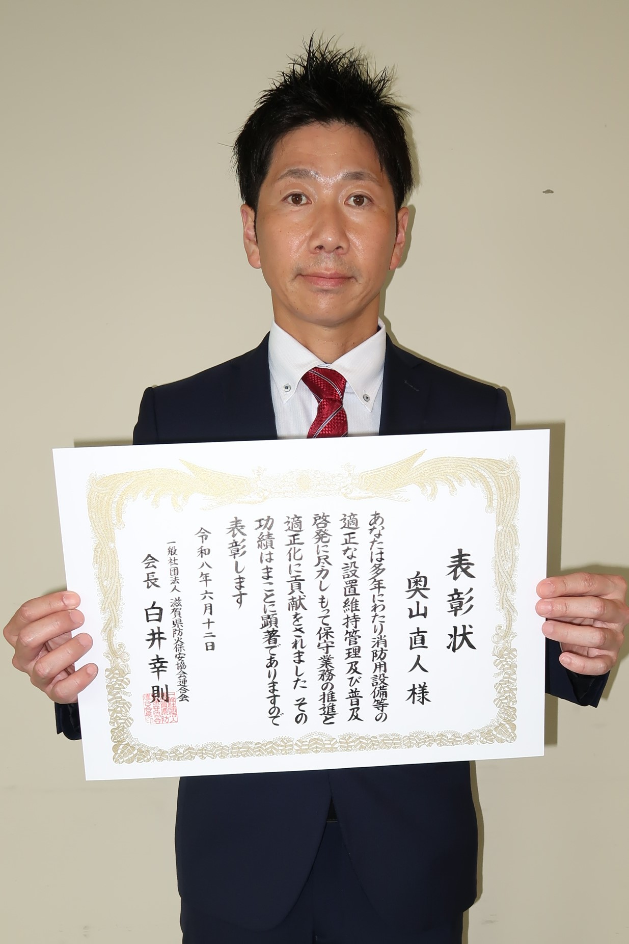 表彰状を両手で持つ男性
