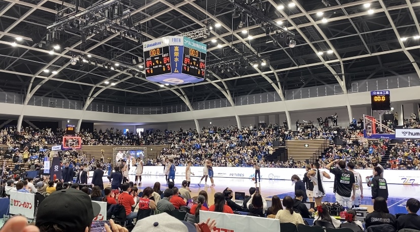 観客が大勢いるバスケ試合中の会場の写真