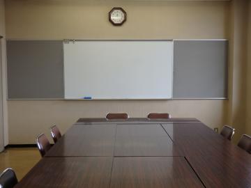 部屋の中央に大きな机と、椅子が並べられた会議室の写真