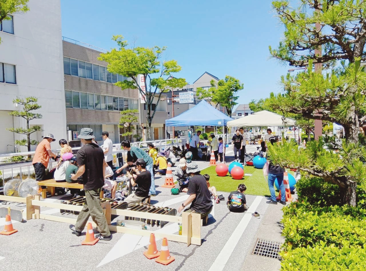 日中のお城通りで多くの人がベンチや人工芝に集まっている様子