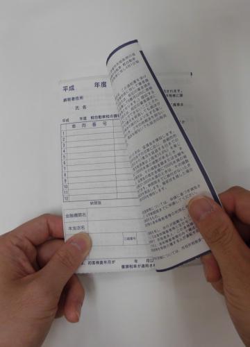 納税通知書（口座振替用）を両手で開いている様子の写真