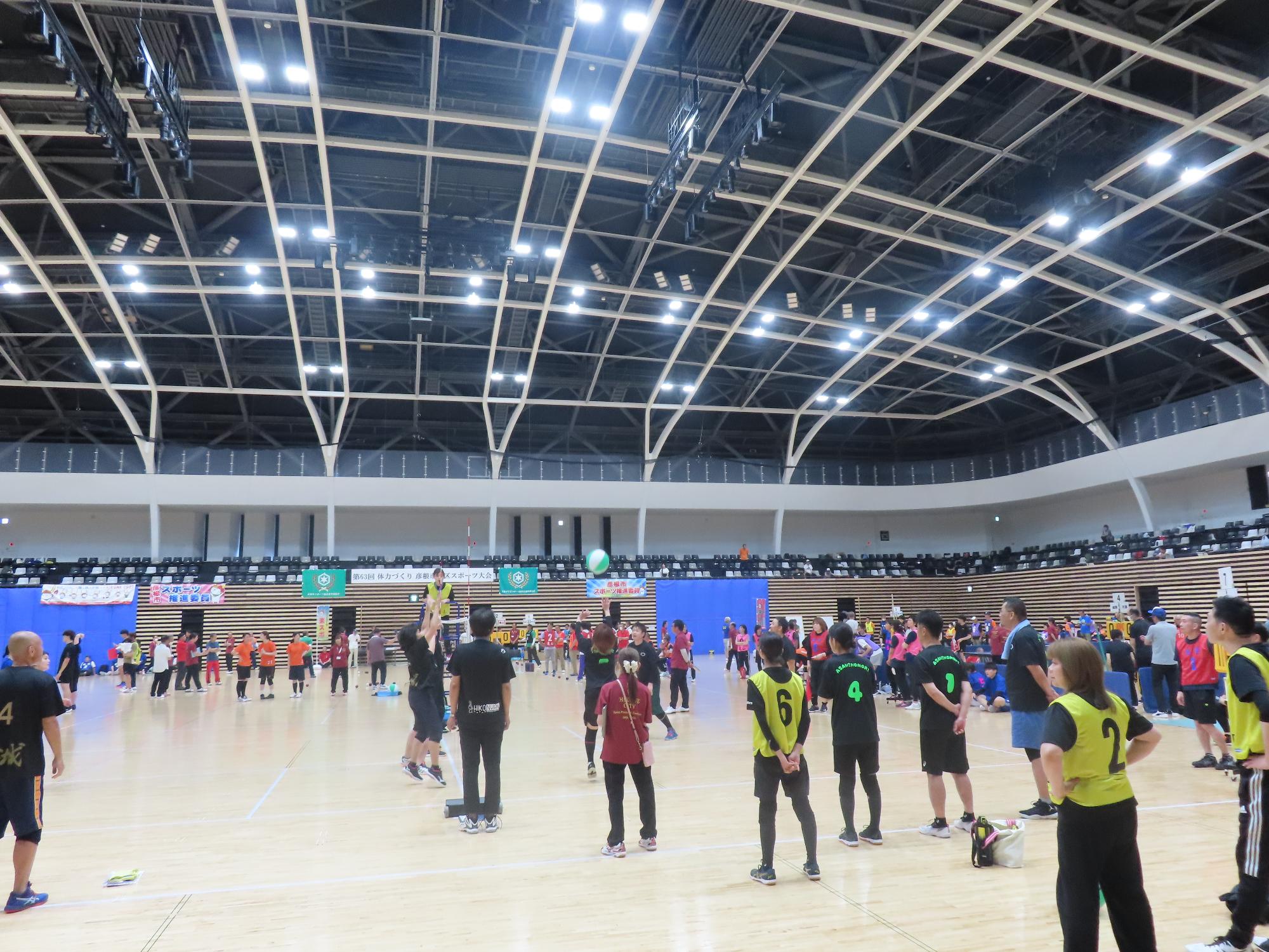 男女混合チームがビーチボールの試合をしている様子の写真