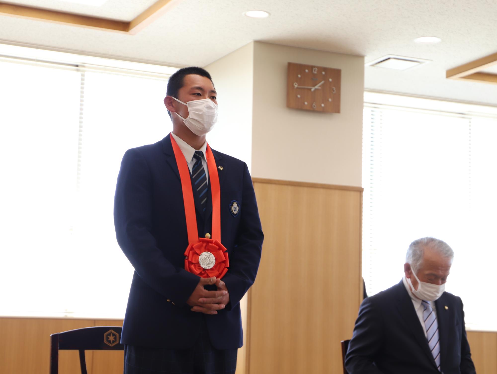 報告会の様子の写真（選手が立って話している）