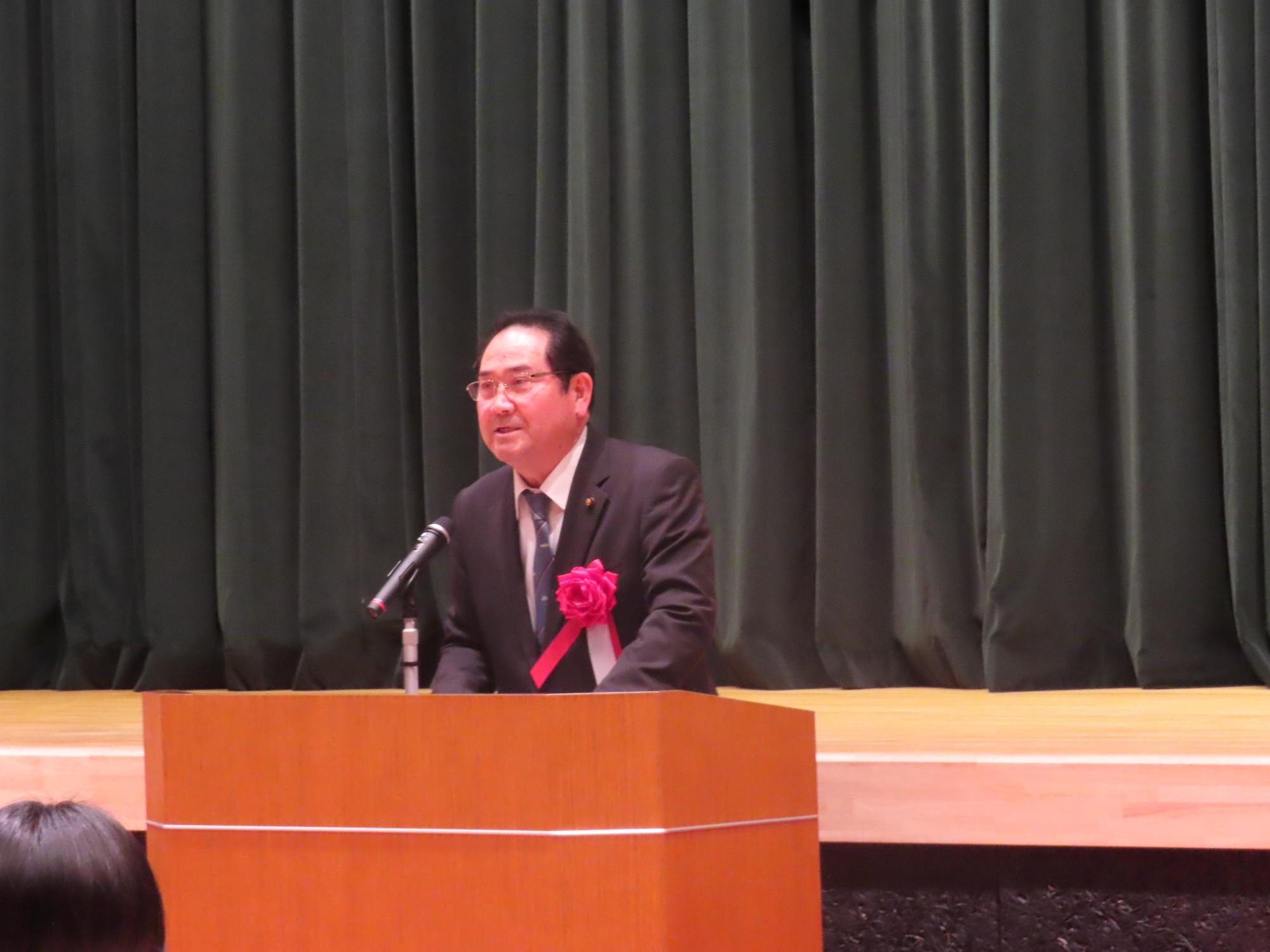 演台で議長が祝辞を述べる様子