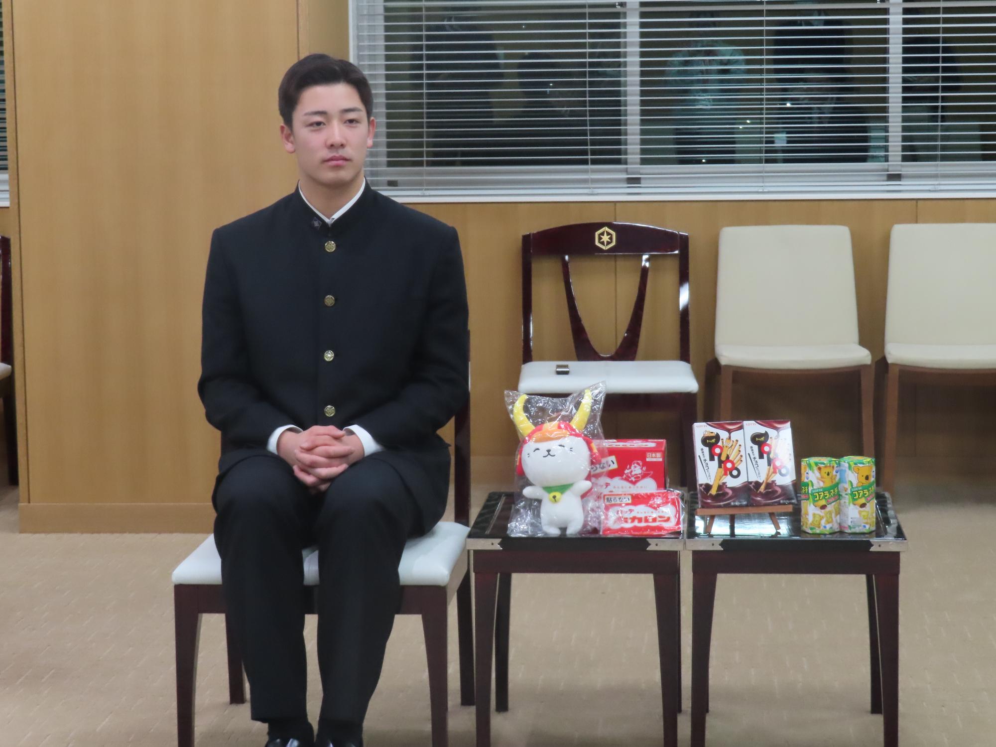 ひこにゃんのぬいぐるみやロッテの製品が並べられた横に座る奥村選手