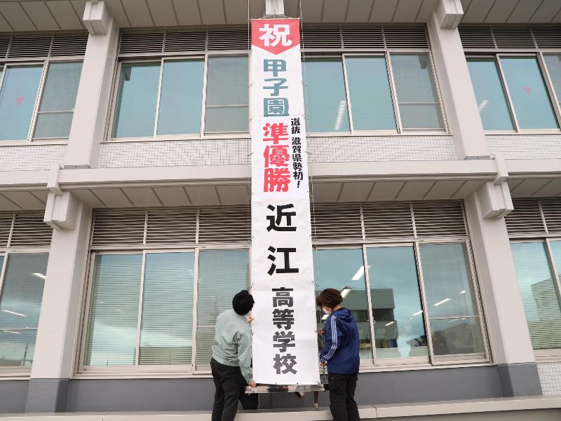 市役所本庁舎壁面に職員が懸垂幕を掲出している写真