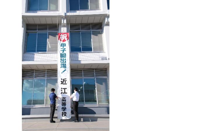 職員が「祝甲子園出場！近江高等学校」と書かれた懸垂幕を掲出している写真