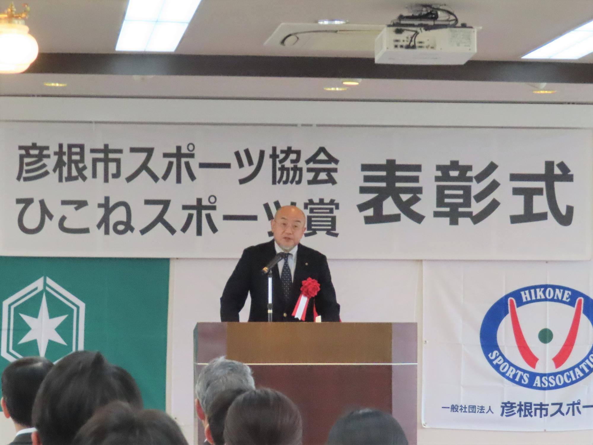 演台で議長が祝辞を述べる様子