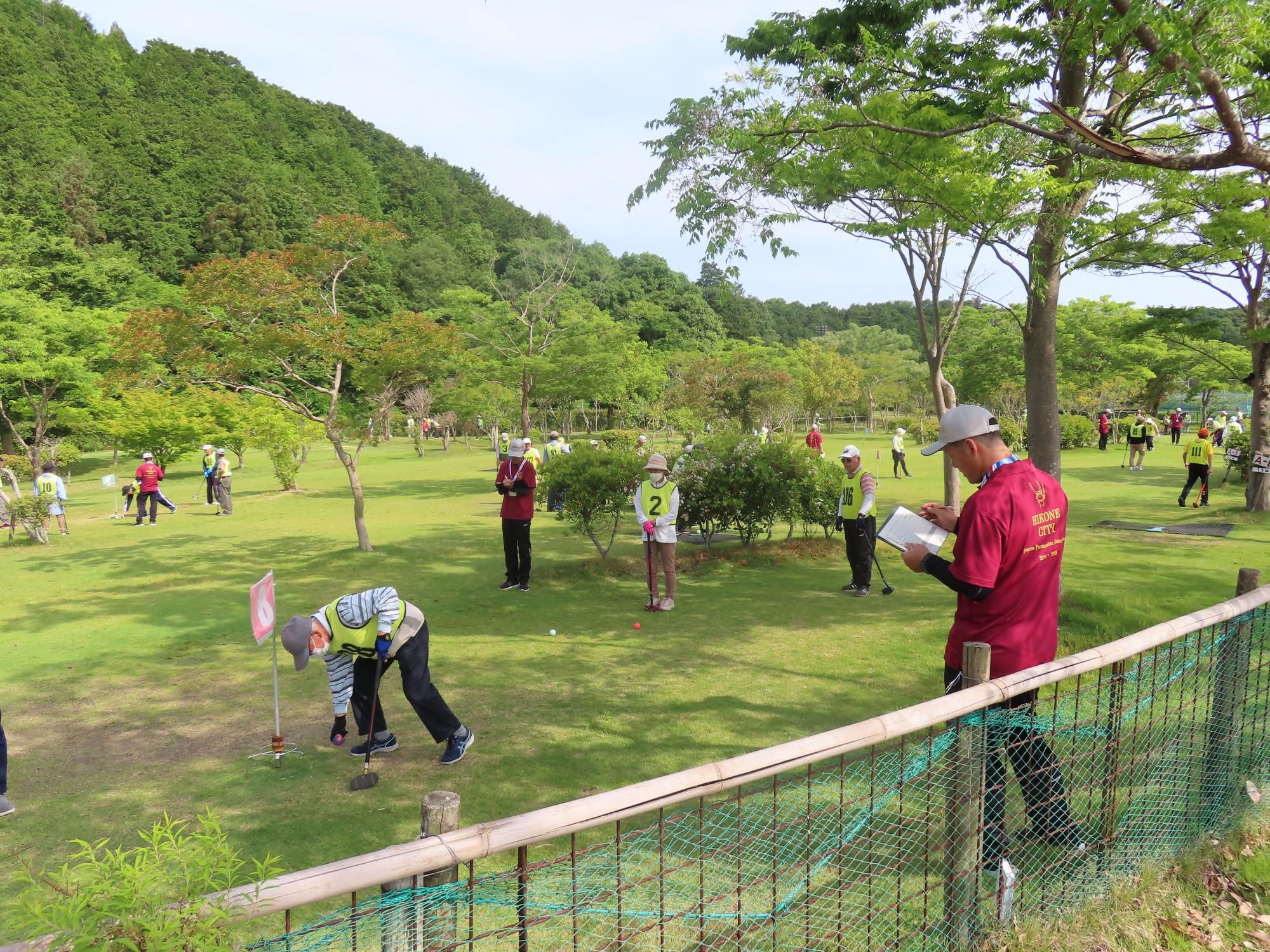 山のふもとの広場でふれあいグラウンドゴルフが行われている様子の写真