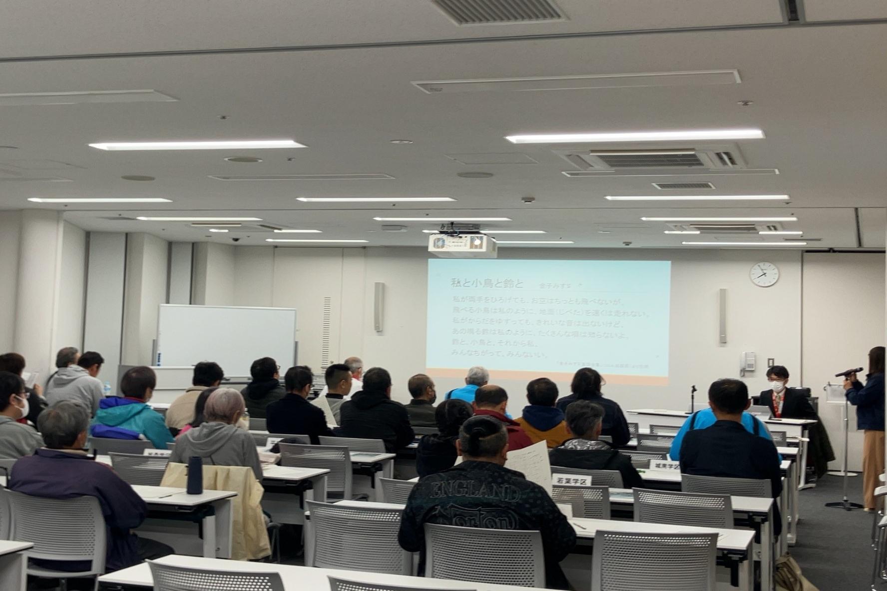 会議室に集まり、前方スクリーンを見て研修を受ける人たちの写真