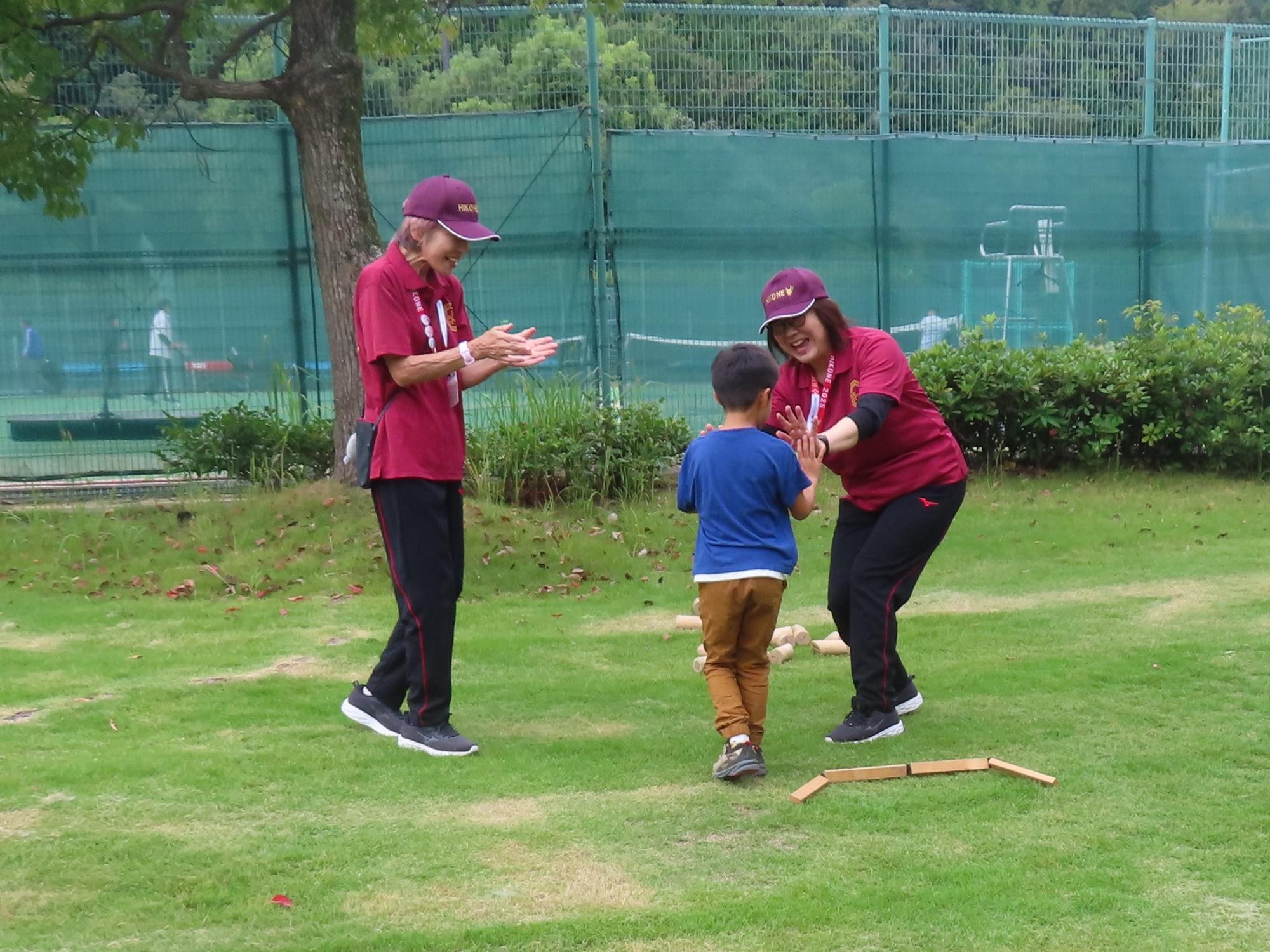 推進委員の女性と子どもがタッチをし、他の推進委員の女性が拍手をしている様子の写真