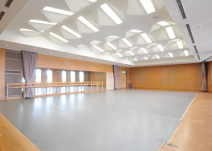 リハーサル室の画像（壁に設置された鏡、シートが引かれた床等の設備がある室内の写真）