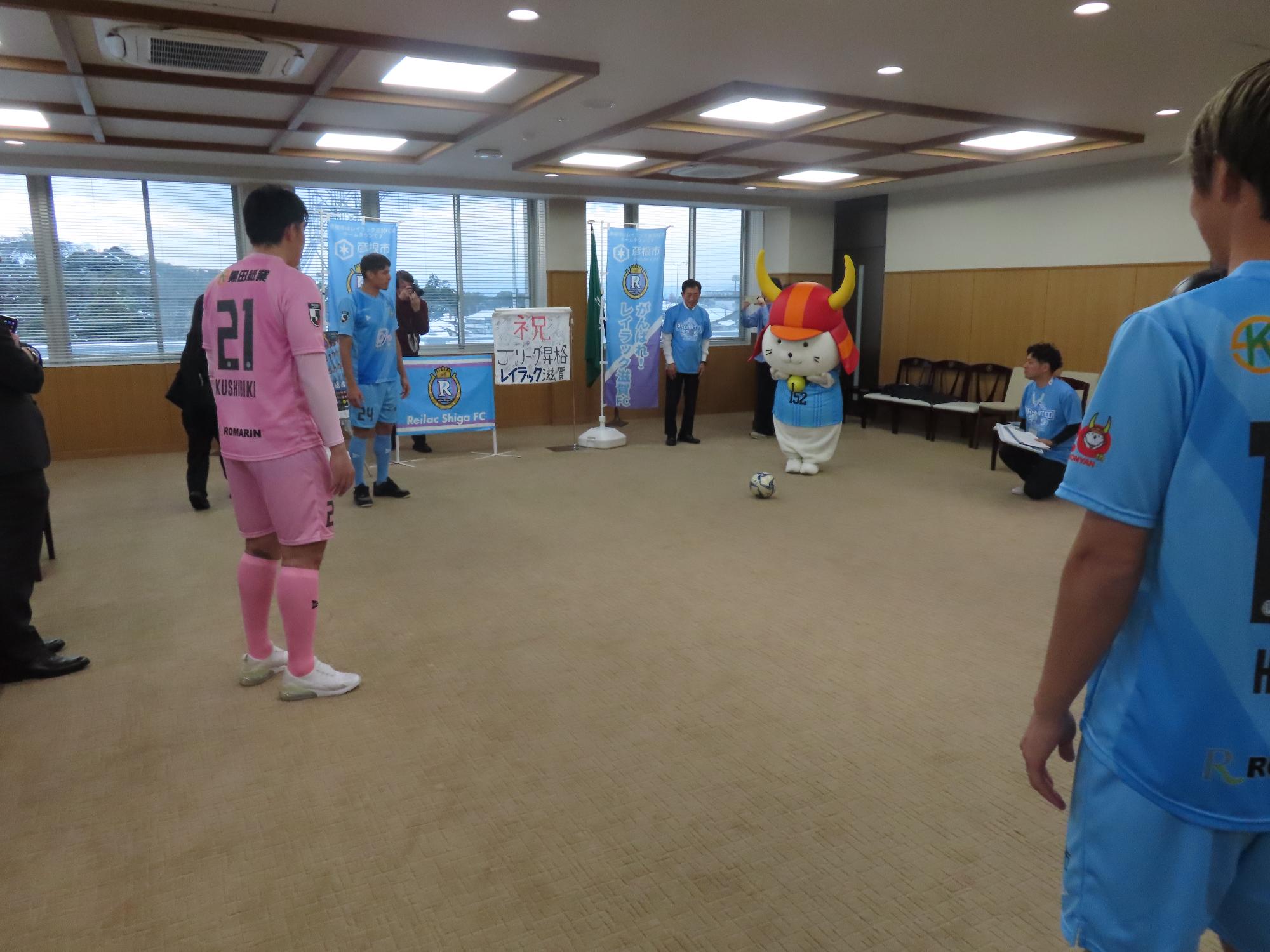 ひこにゃんとが選手に向かってボールを蹴ろうとする様子の写真