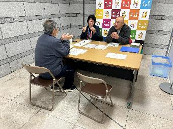 机を挟んで意見交換する男性と議員二人の様子