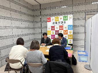 机を挟んで意見交換する女性3人とと議員2人の様子