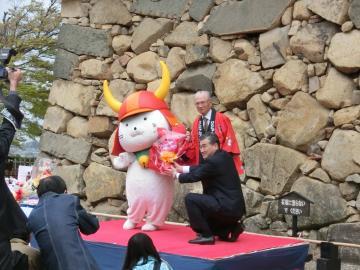 石垣の前で花束贈呈を右側から撮影した写真