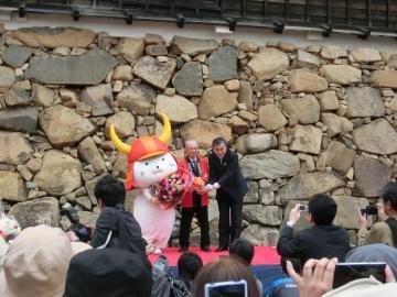 石垣の前で花束贈呈を正面から撮影した写真