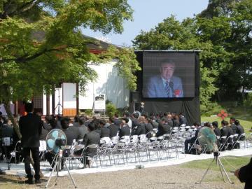 会場に設置された大型スクリーンに映し出された市長の写真