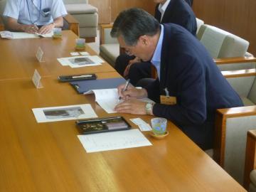 協定書にサインをする市長の写真