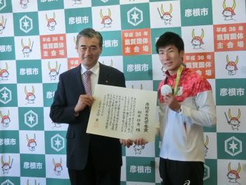 メダルを首にかけた桐生選手と表彰状を持った市長の写真