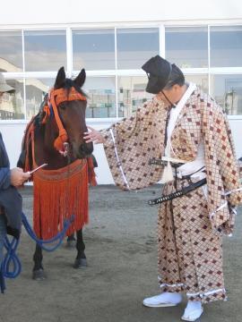 行列の前に馬に挨拶をする市長の写真