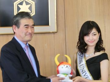 ミスユニバース・ジャパン日本代表にひこにゃんのぬいぐるみをプレゼントする市長の写真