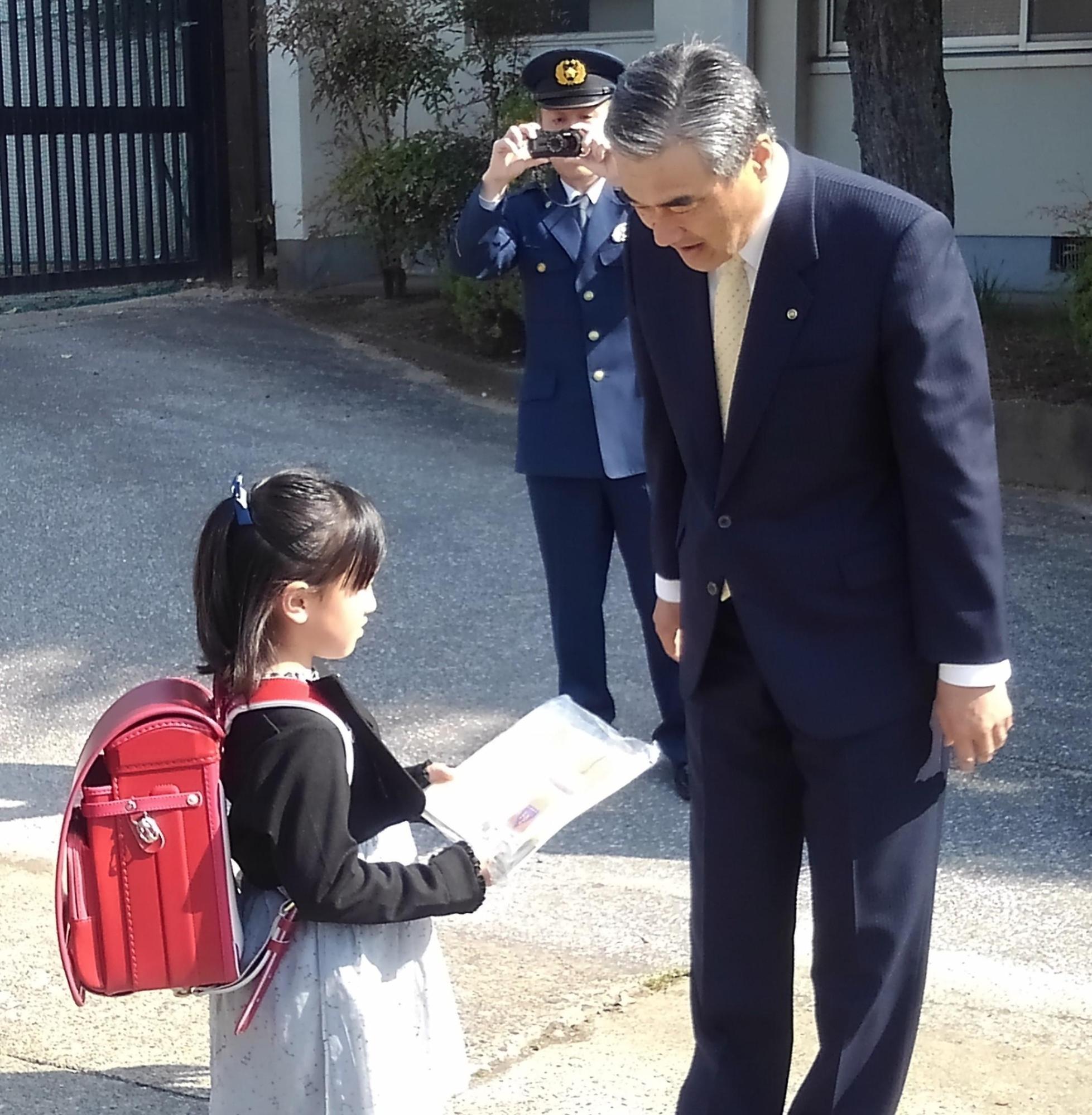 小学生の女の子にチラシを渡している市長の写真