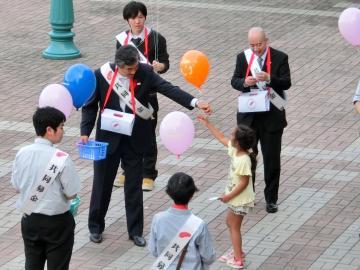 街頭で子供たちに風船を配っている市長の写真