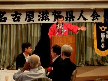 赤いはっぴを着た市長が壇上で挨拶している写真