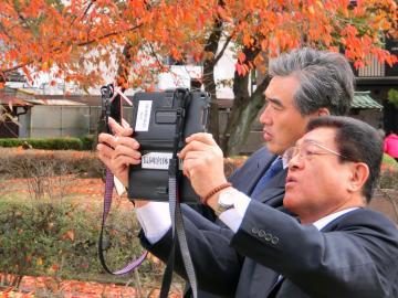 史跡長岡宮跡で機器を手に復元アプリを見ている市長の写真