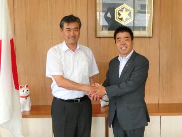 三日月知事と市長が両手で握手をしている写真