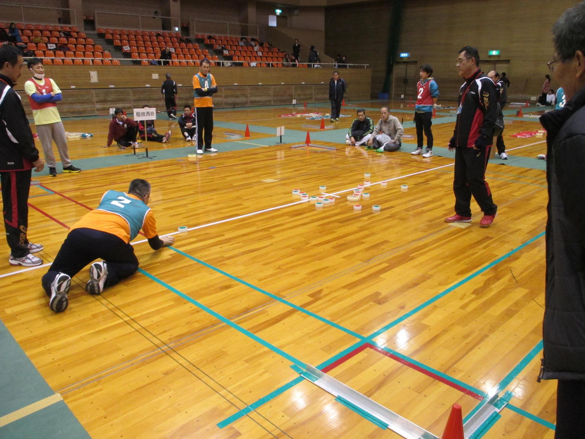 スタートポジションから相手の駒を狙って投げようとしている参加者の写真