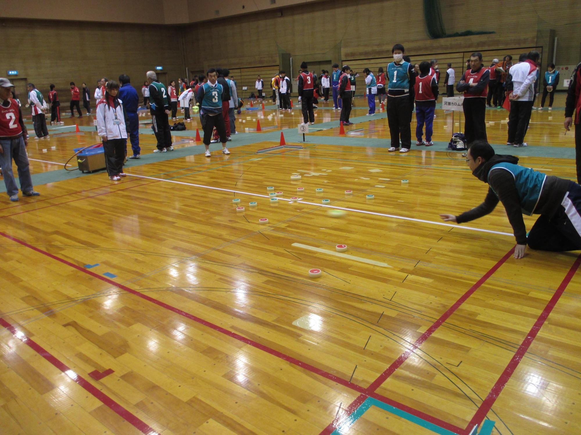 競技者の男性がコート内で手玉を投げている写真