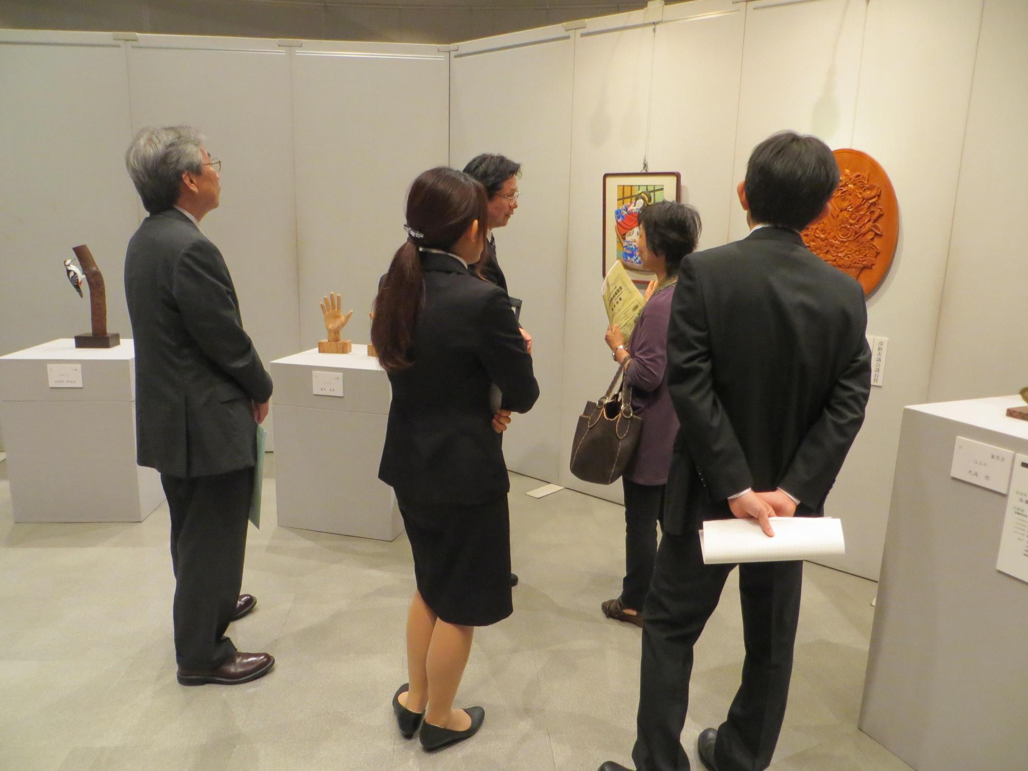 彫刻部門の展示品と展示品を見学している来場者の写真