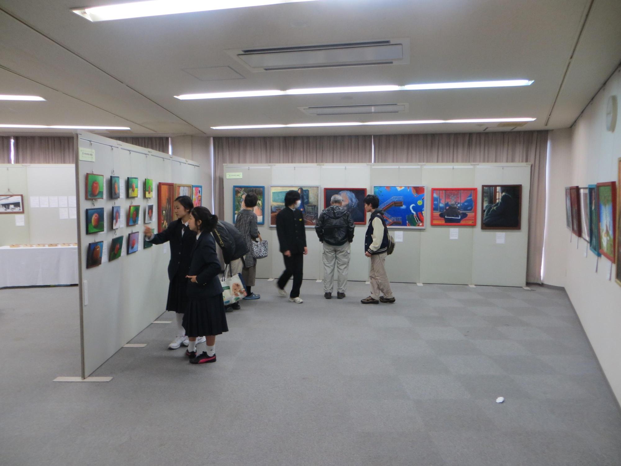 研修室に展示された作品と見学している人々の写真