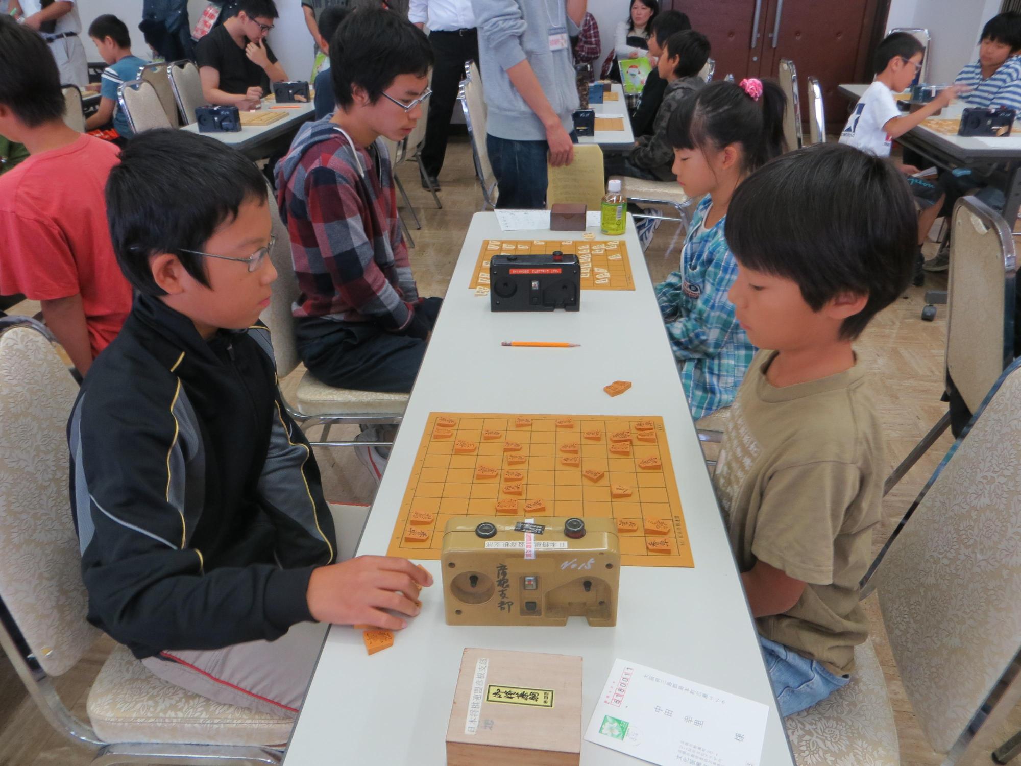 「直弼杯将棋大会」で小学生の男児同志で戦っている写真