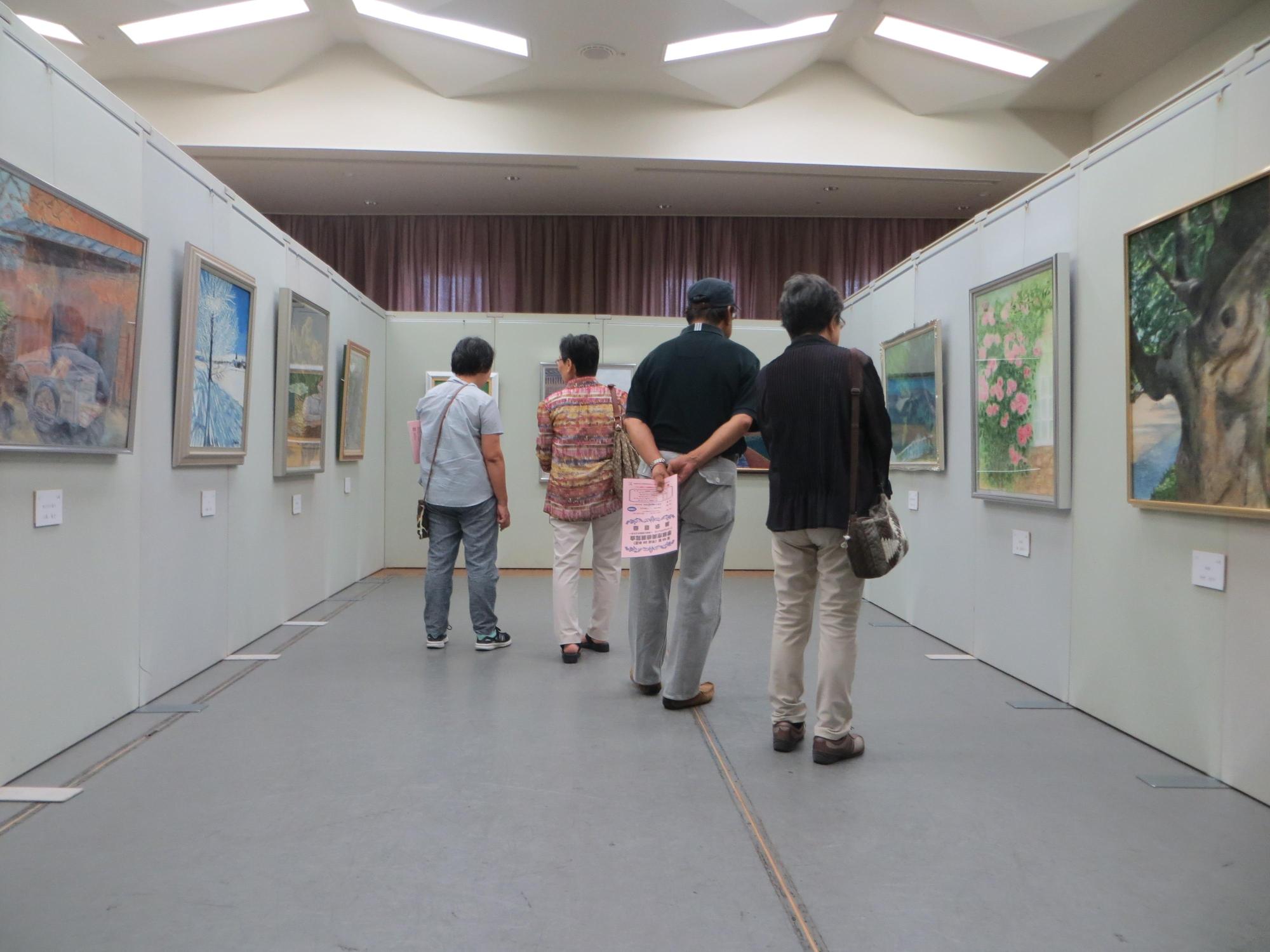 洋画部門の展示作品を見学している来場者の写真