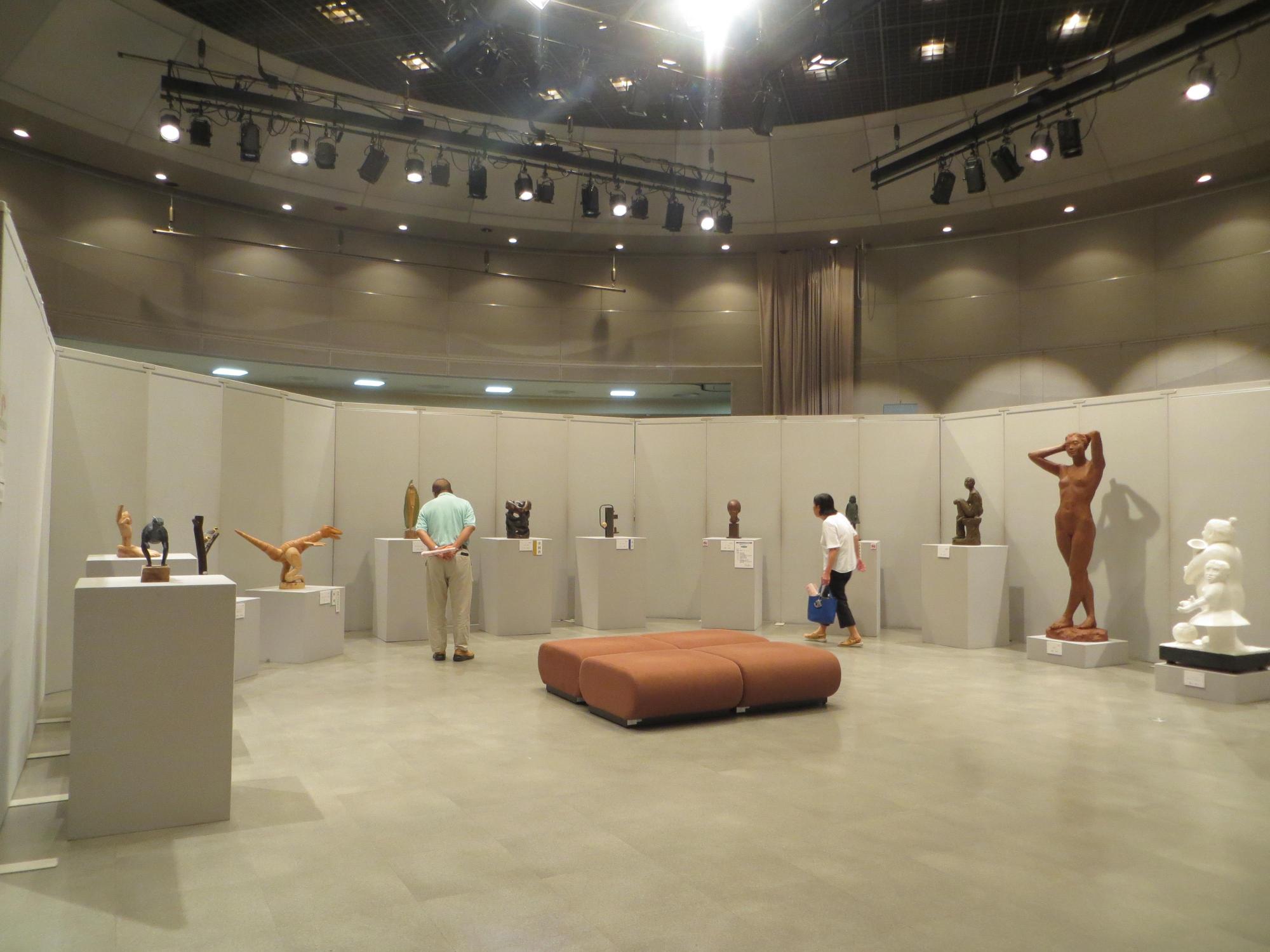 彫刻部門の展示作品を見学している来場者の写真